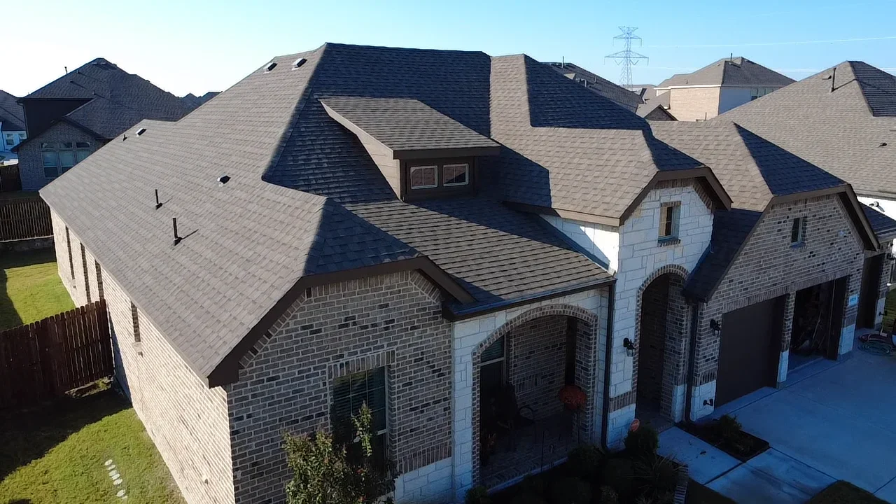 Two-story brick home with multi-plane architectural shingle roof installation in gray and charcoal