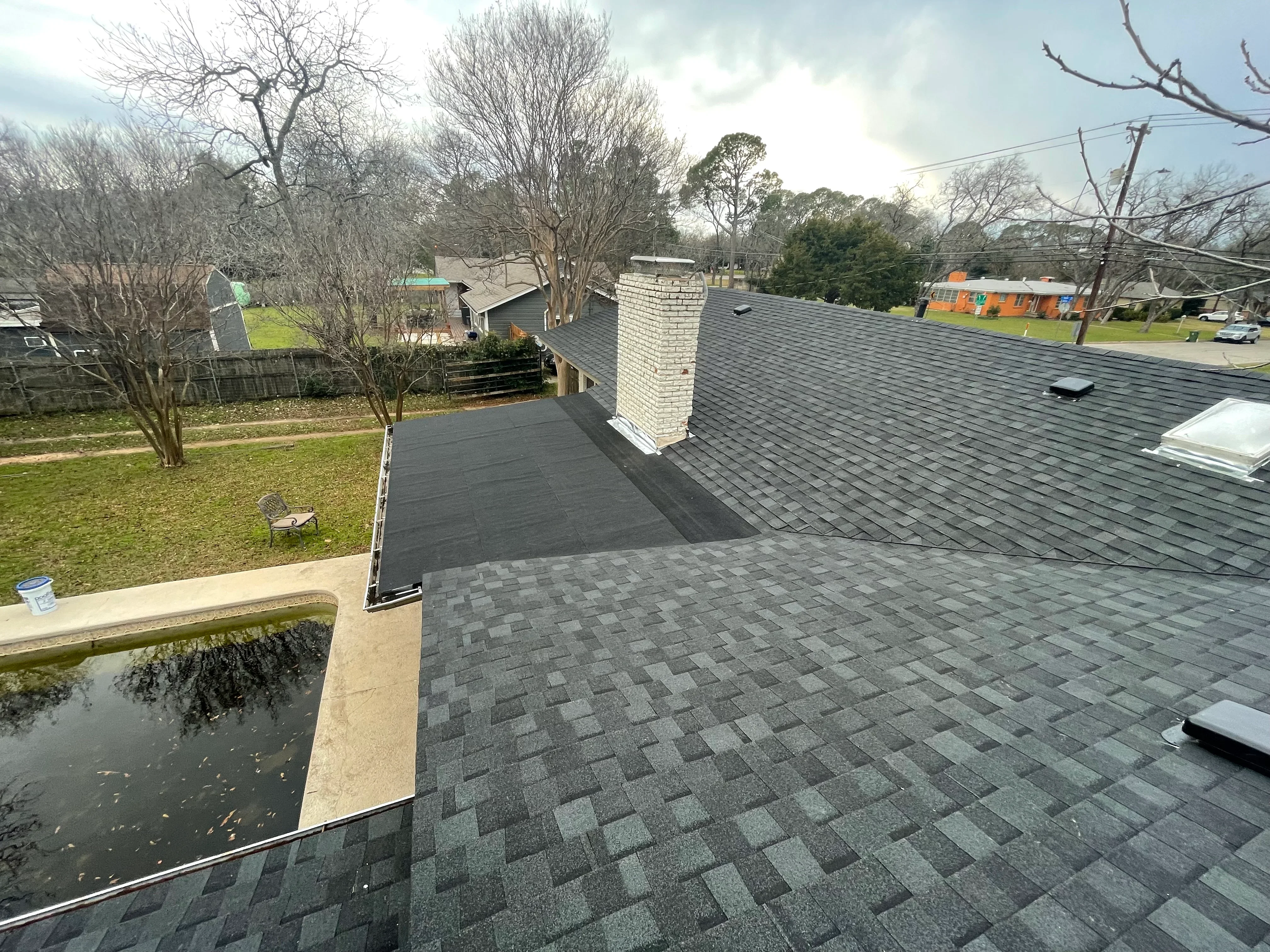 Charcoal gray architectural shingles with white brick chimney on residential roof