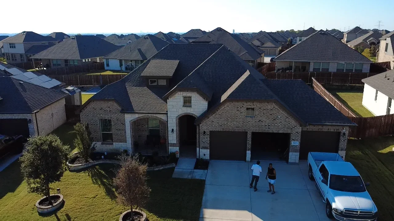 Dark architectural shingle roof on two-story brick home with multiple peaks and valleys