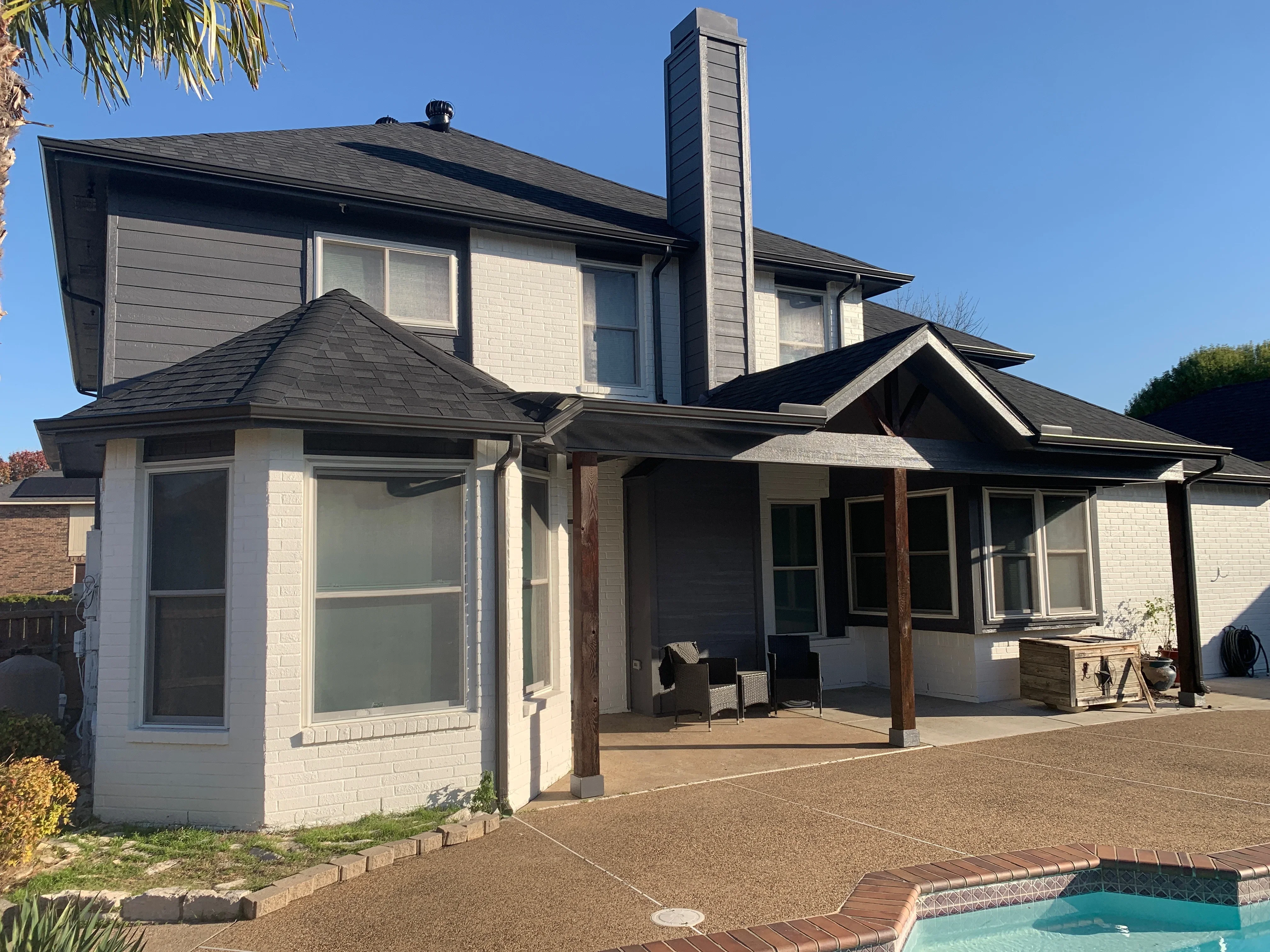 Two-story home with new black architectural shingle roof, brick chimney, and multiple roof planes