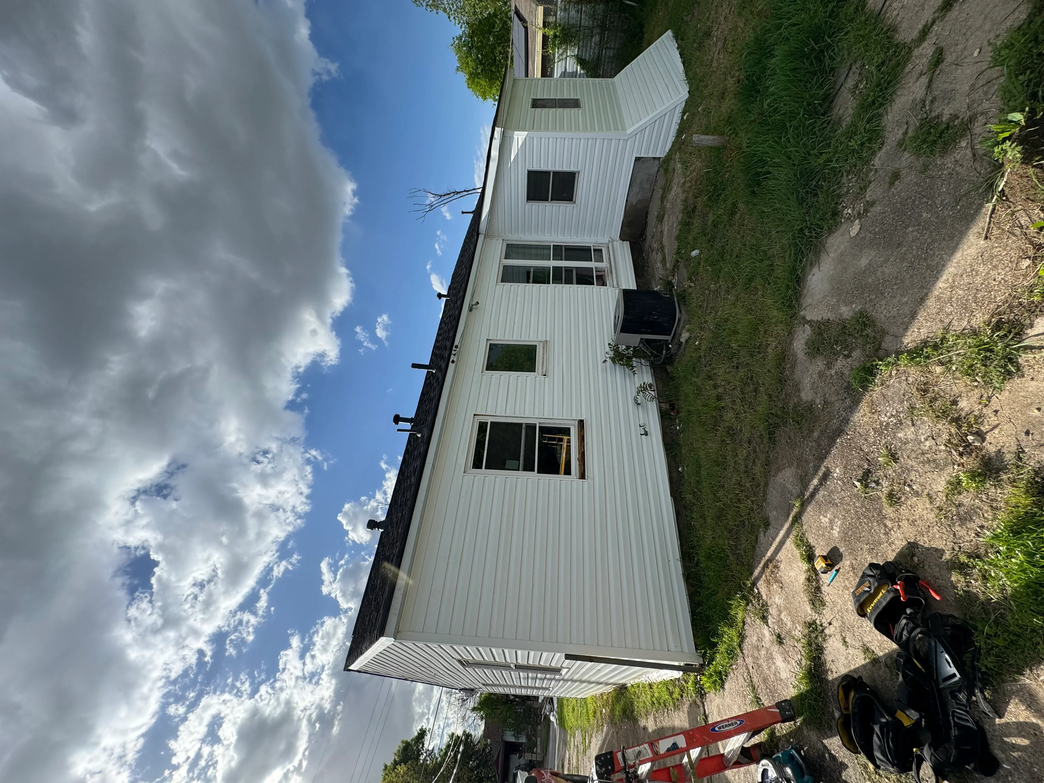Standing seam metal roof installation with gray corrugated panels and multiple window openings