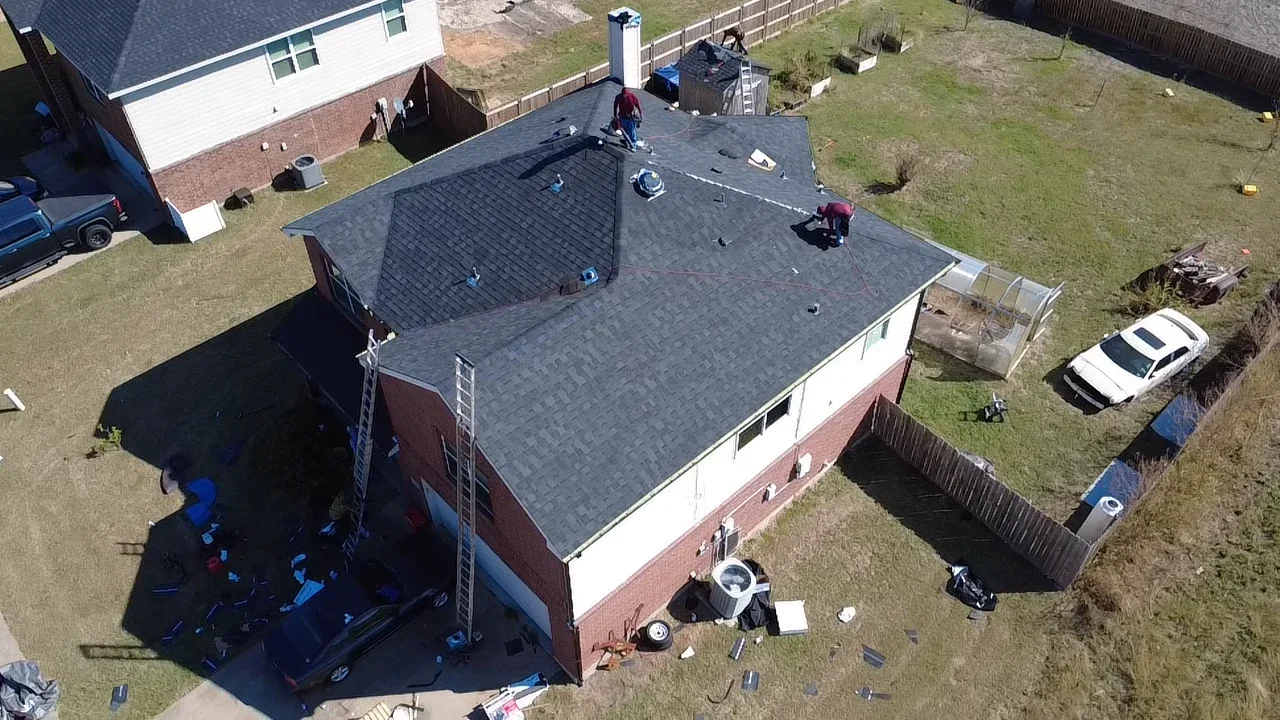 Aerial view of residential roof replacement with gray architectural shingles on brick home