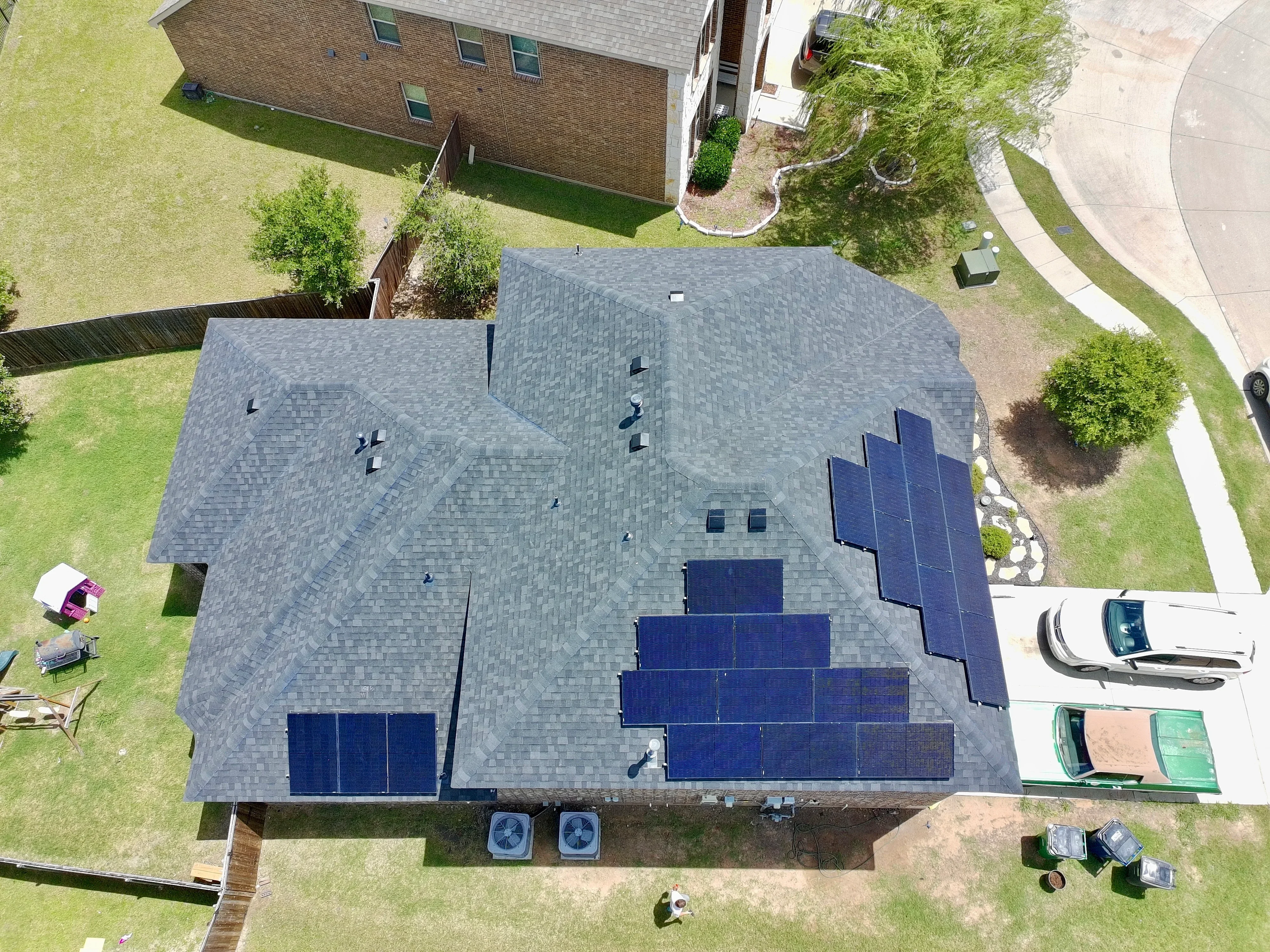 Aerial view of residential roof with gray architectural shingles and installed solar panel array