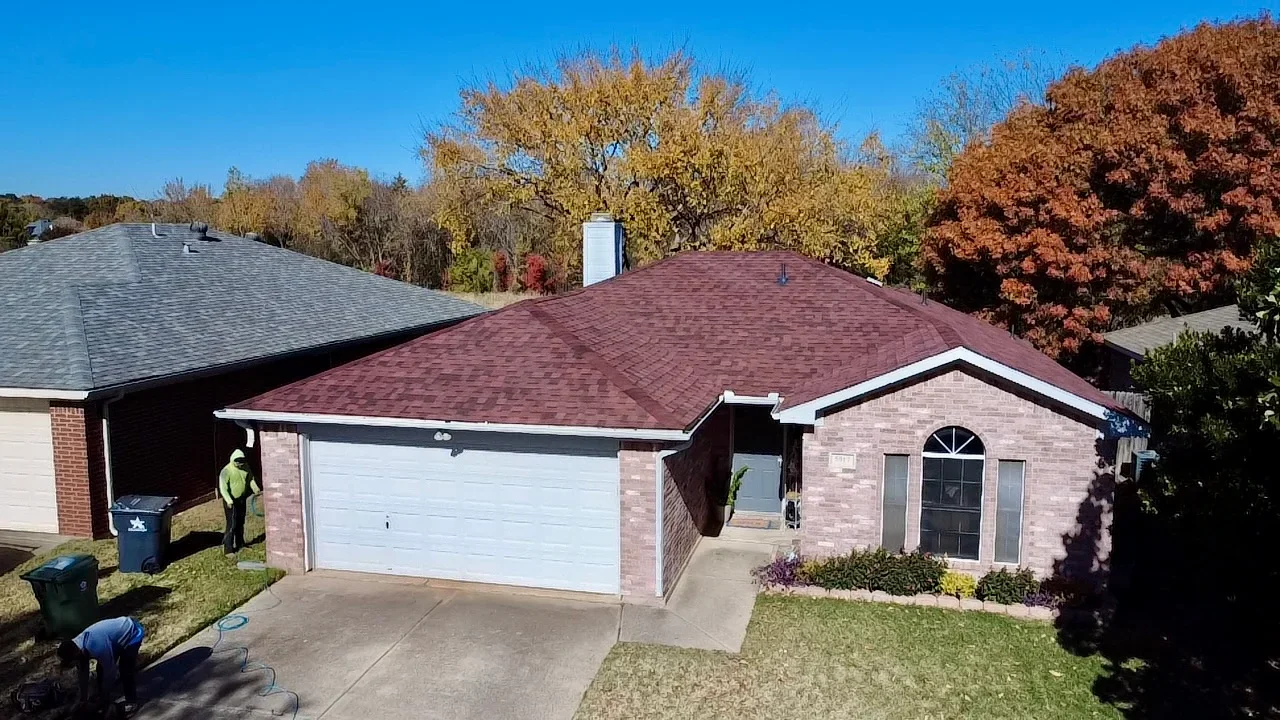Burgundy architectural shingle roof on brick home with white trim and chimney flashing
