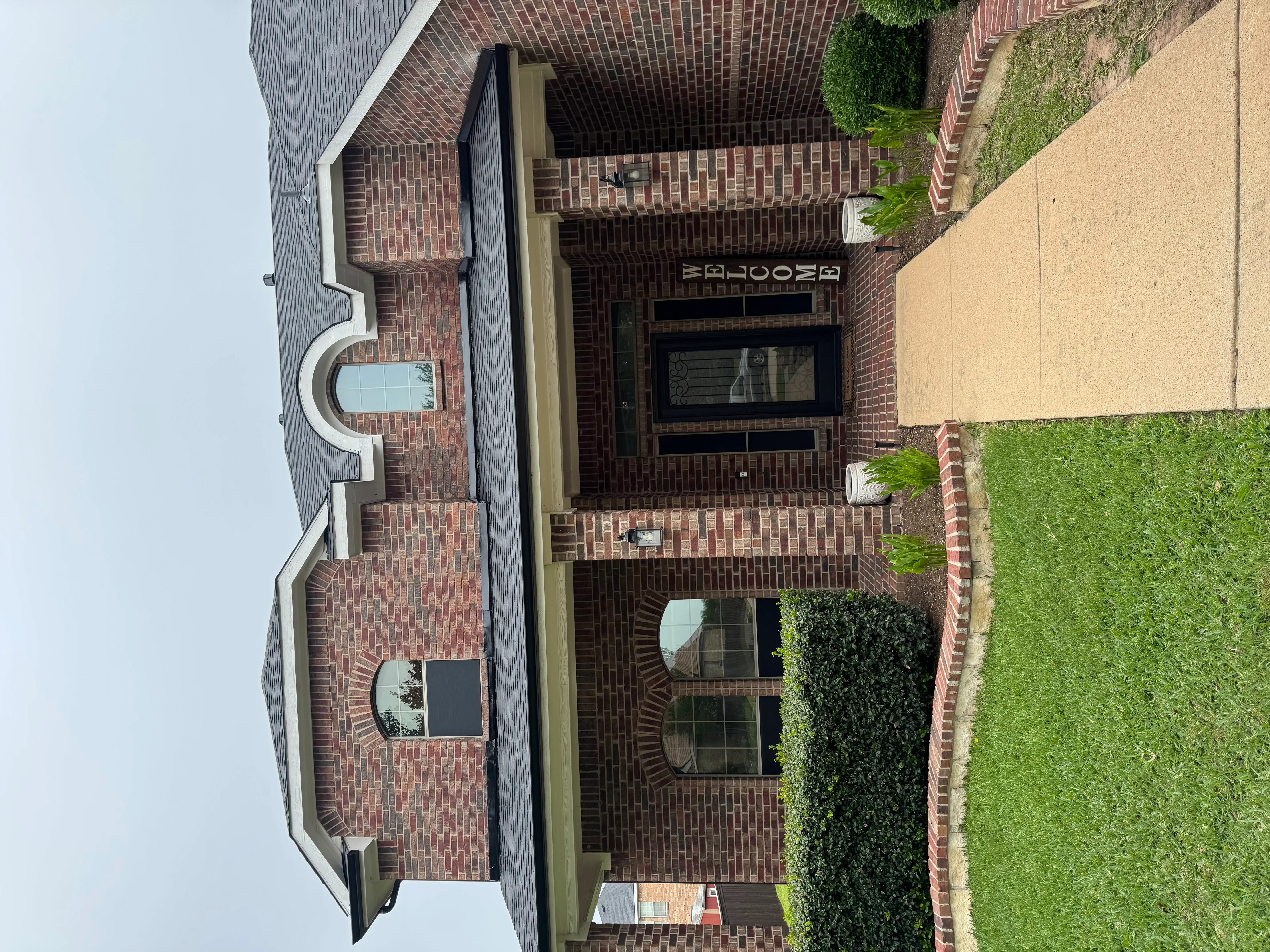 Two-story brick home with new dark asphalt shingle roof installation and white trim accents