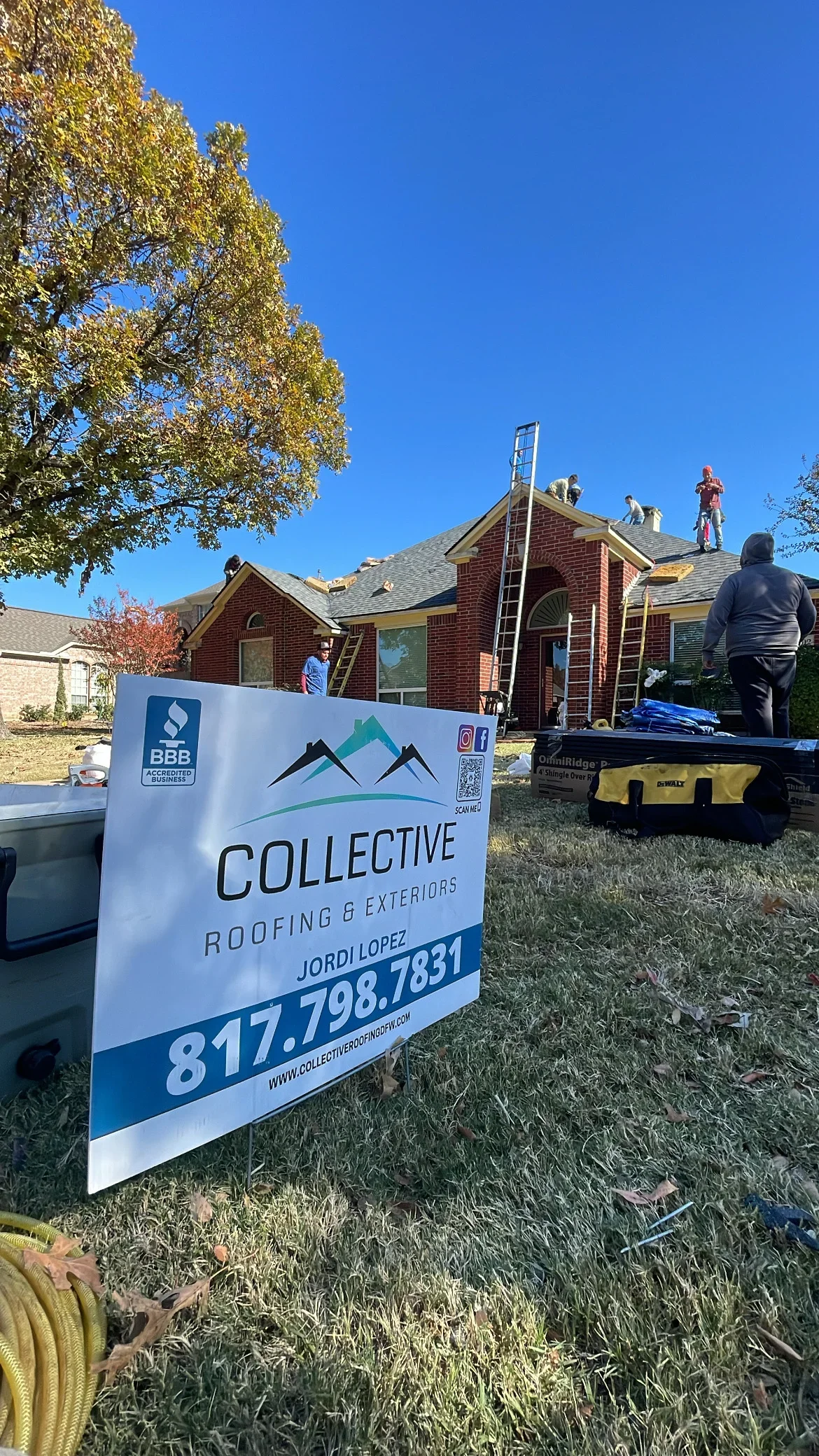 Brick home with new gray architectural shingles, ladder and crew on roof during installation