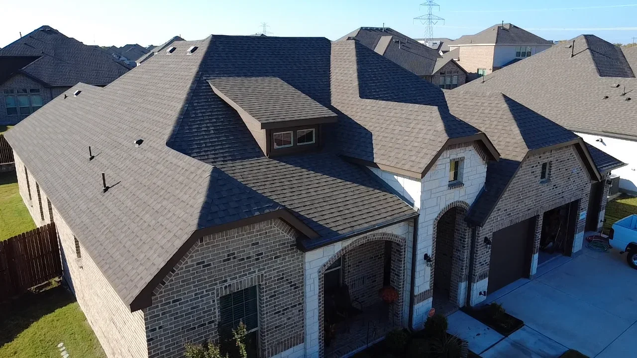 Two-story brick home with multi-pitch asphalt shingle roof, dormers, and complex architectural design