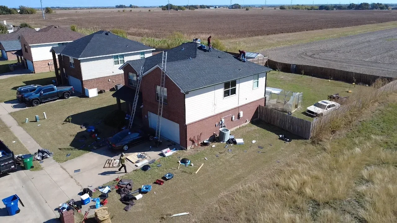 Two-story brick home with new dark gray architectural shingle roof installation in progress