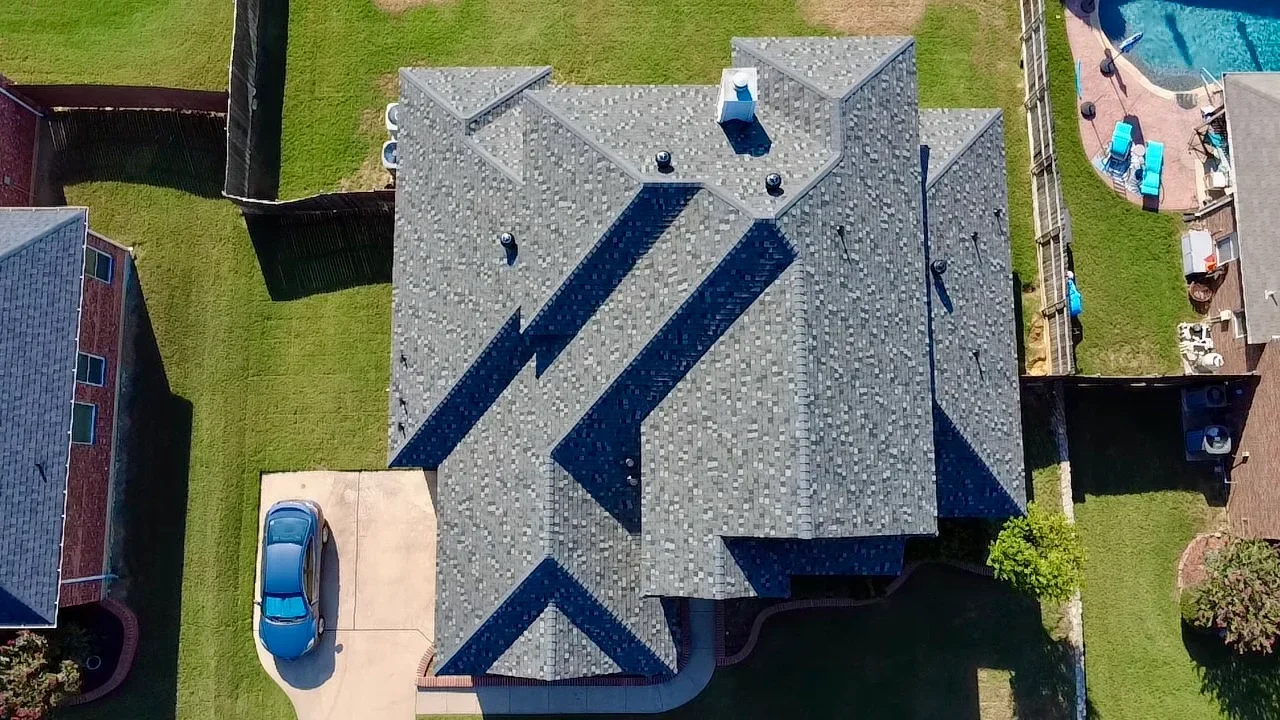 Gray and dark blue architectural shingles installed on multi-pitched residential roof with geometric pattern design