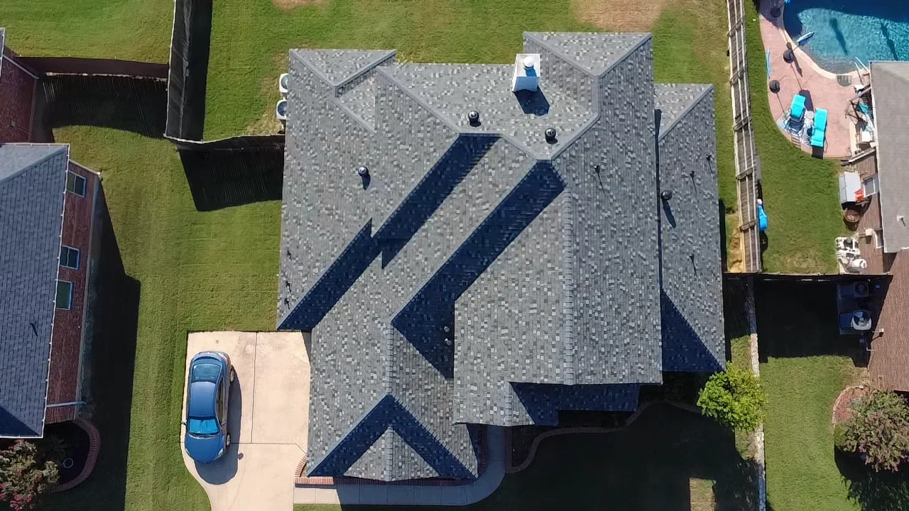 Aerial view of residential roof with gray and dark navy architectural shingles in geometric pattern