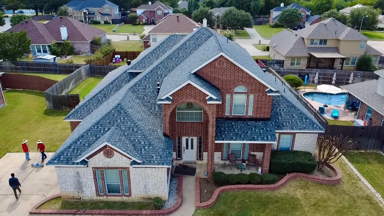 Two-story brick home with blue-gray architectural shingle roof, multiple gables and dormers