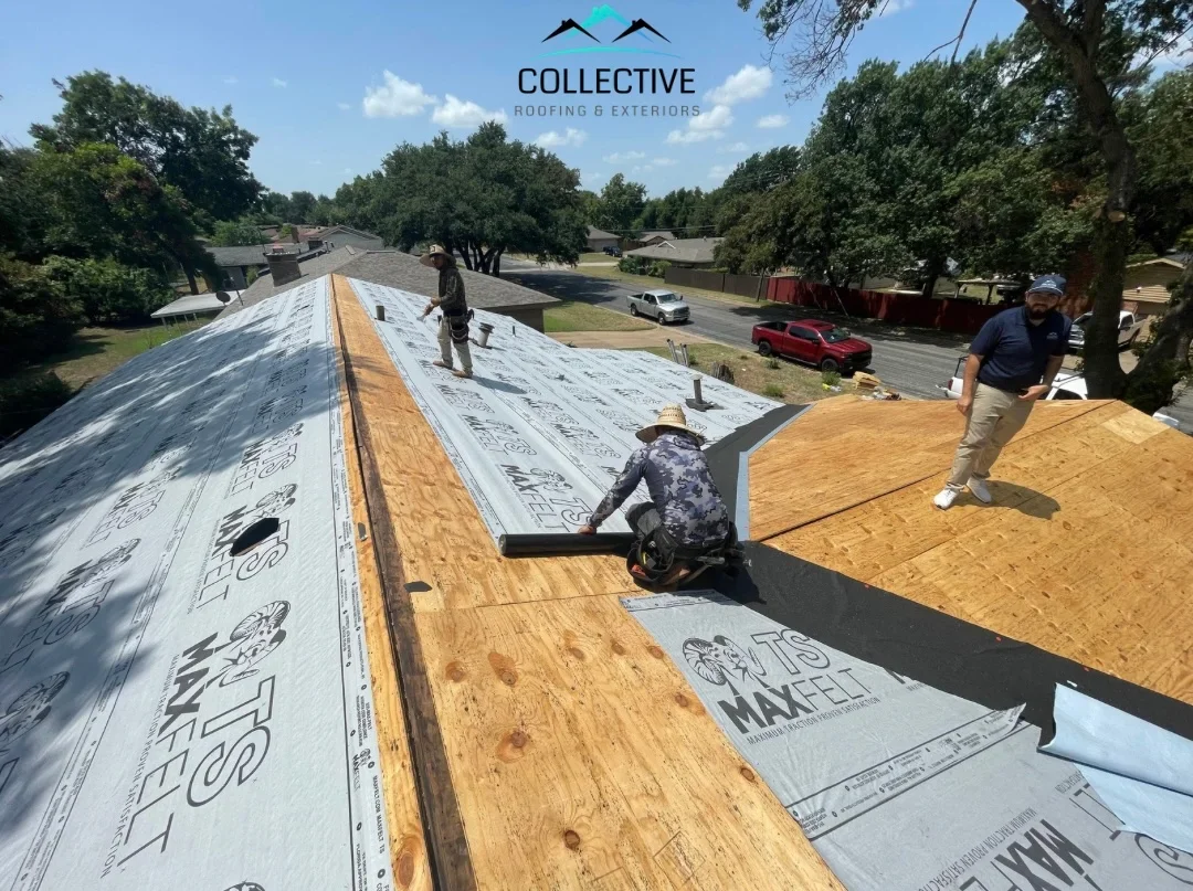 Roofers installing plywood sheathing and synthetic underlayment on pitched residential roof