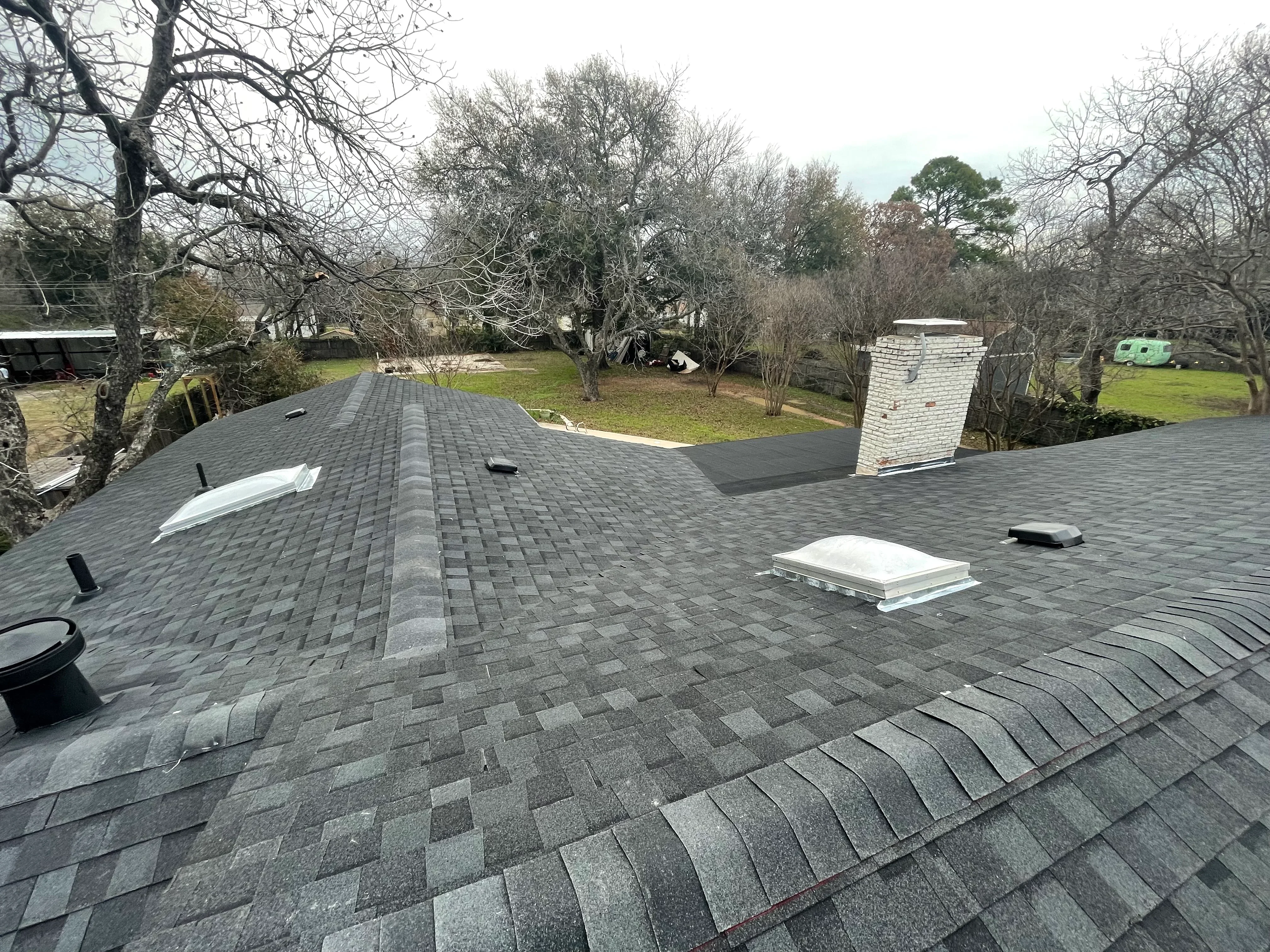 New asphalt shingle roof with gray architectural shingles, ridge cap, and roof vents installed