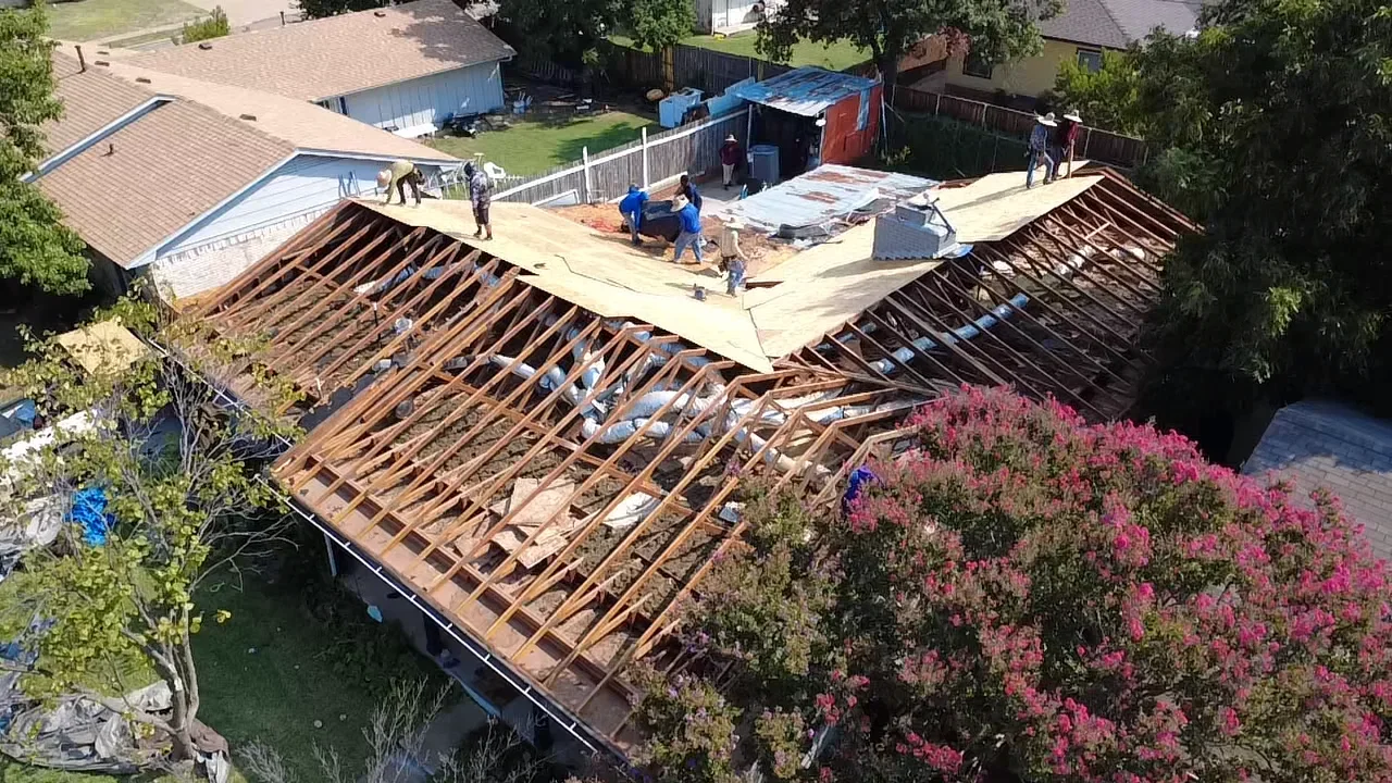 Wooden roof trusses and yellow OSB decking during active roof framing installation on residential addition