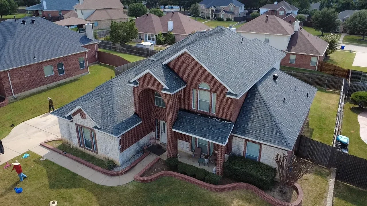 Aerial view of brick home with new charcoal gray dimensional shingle roof installation on multiple planes
