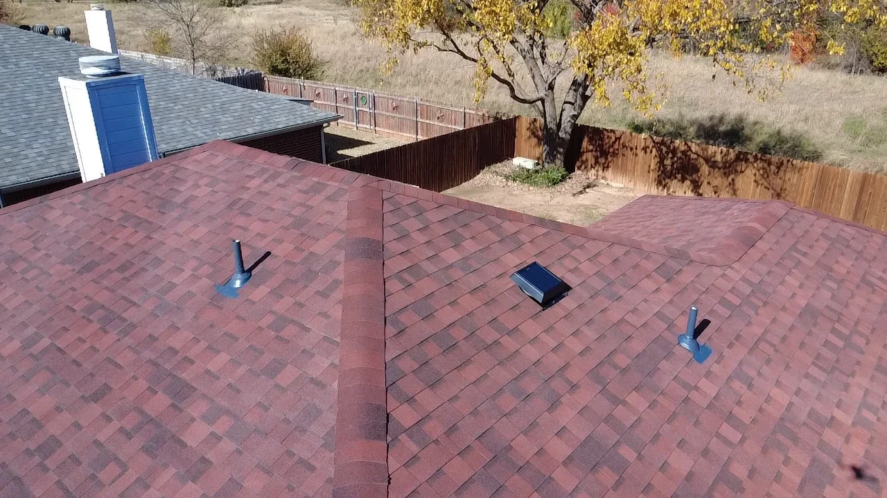 Burgundy architectural shingles with ridge vent and roof penetrations on completed installation