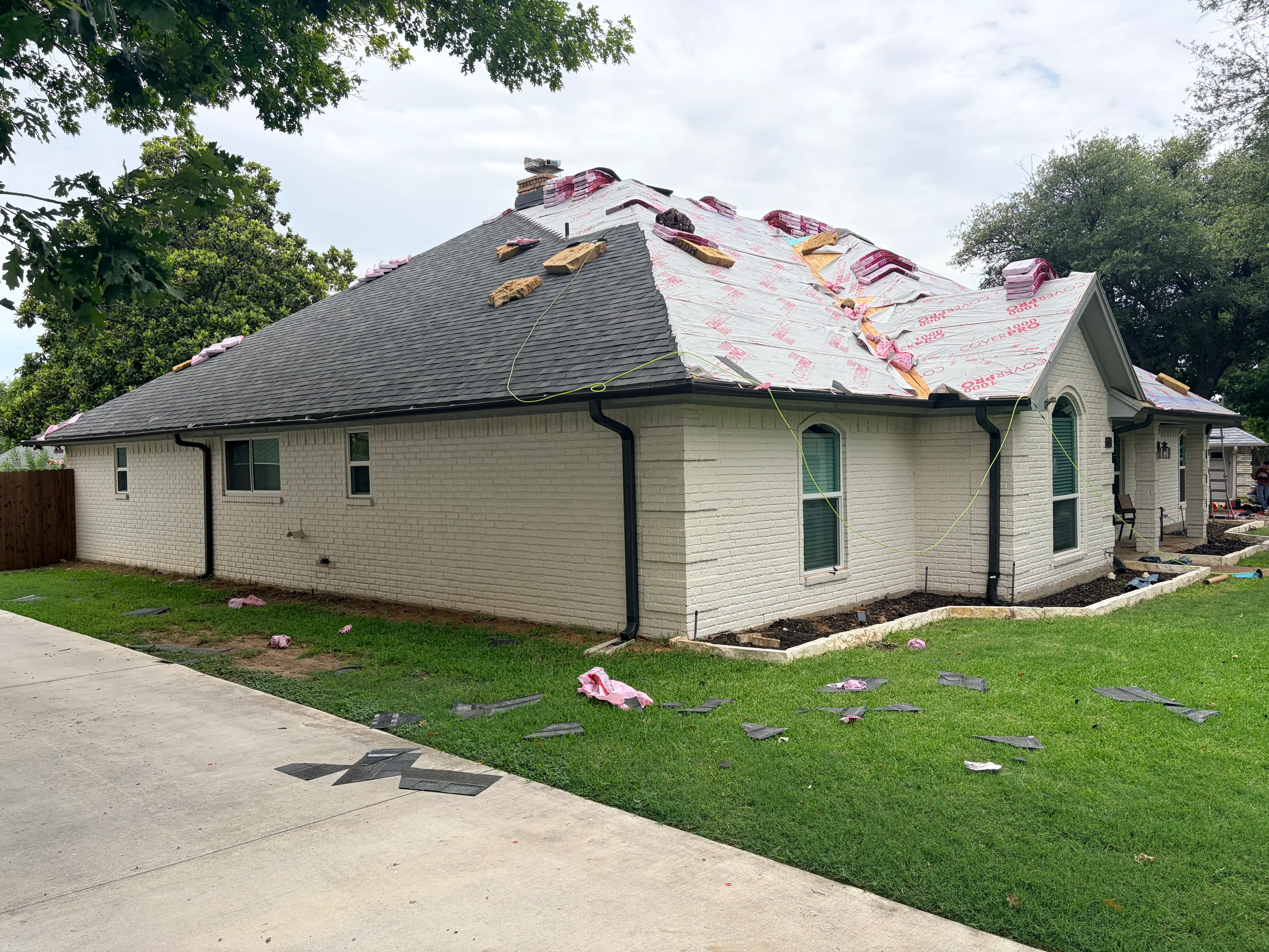 Residential roof replacement with gray architectural shingles and protective underlayment during installation