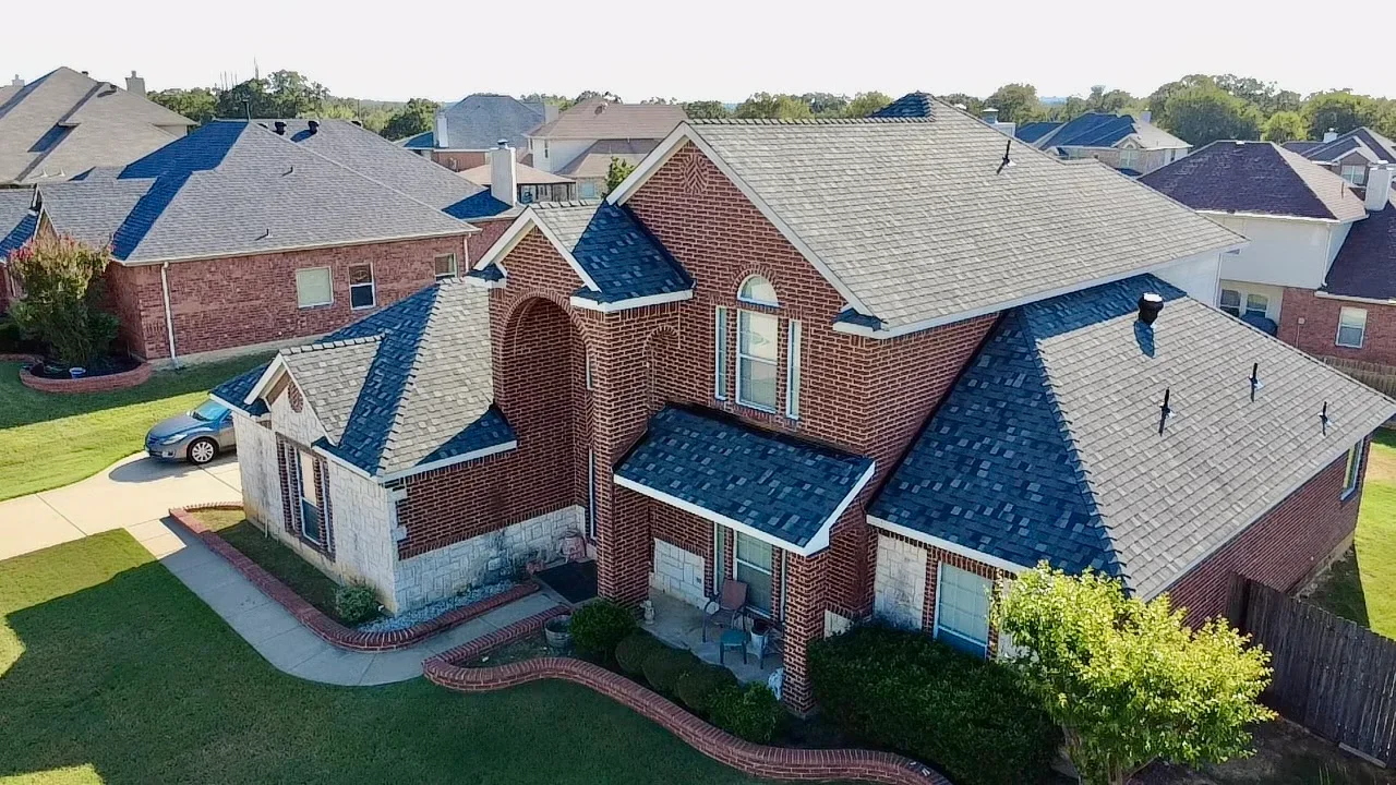 Two-story brick home with new multi-slope asphalt shingle roof in blue and gray tones