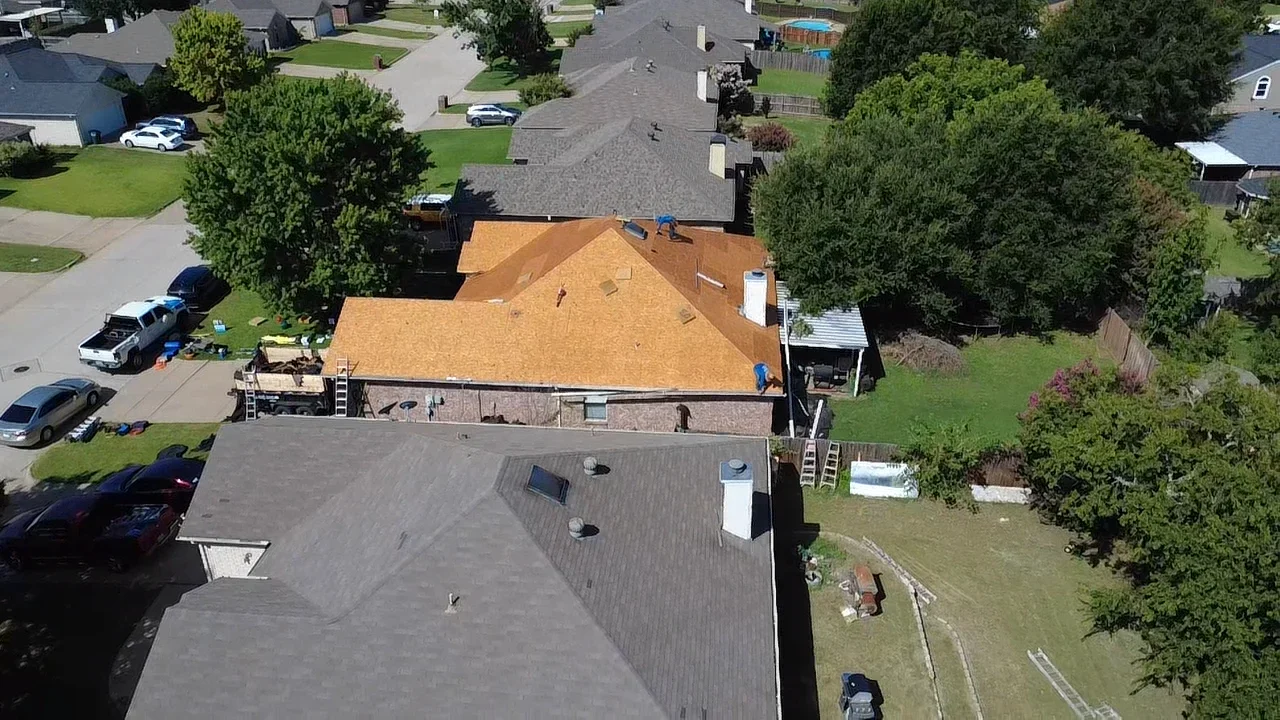 Aerial view of residential roof replacement with golden architectural shingles and new underlayment installation