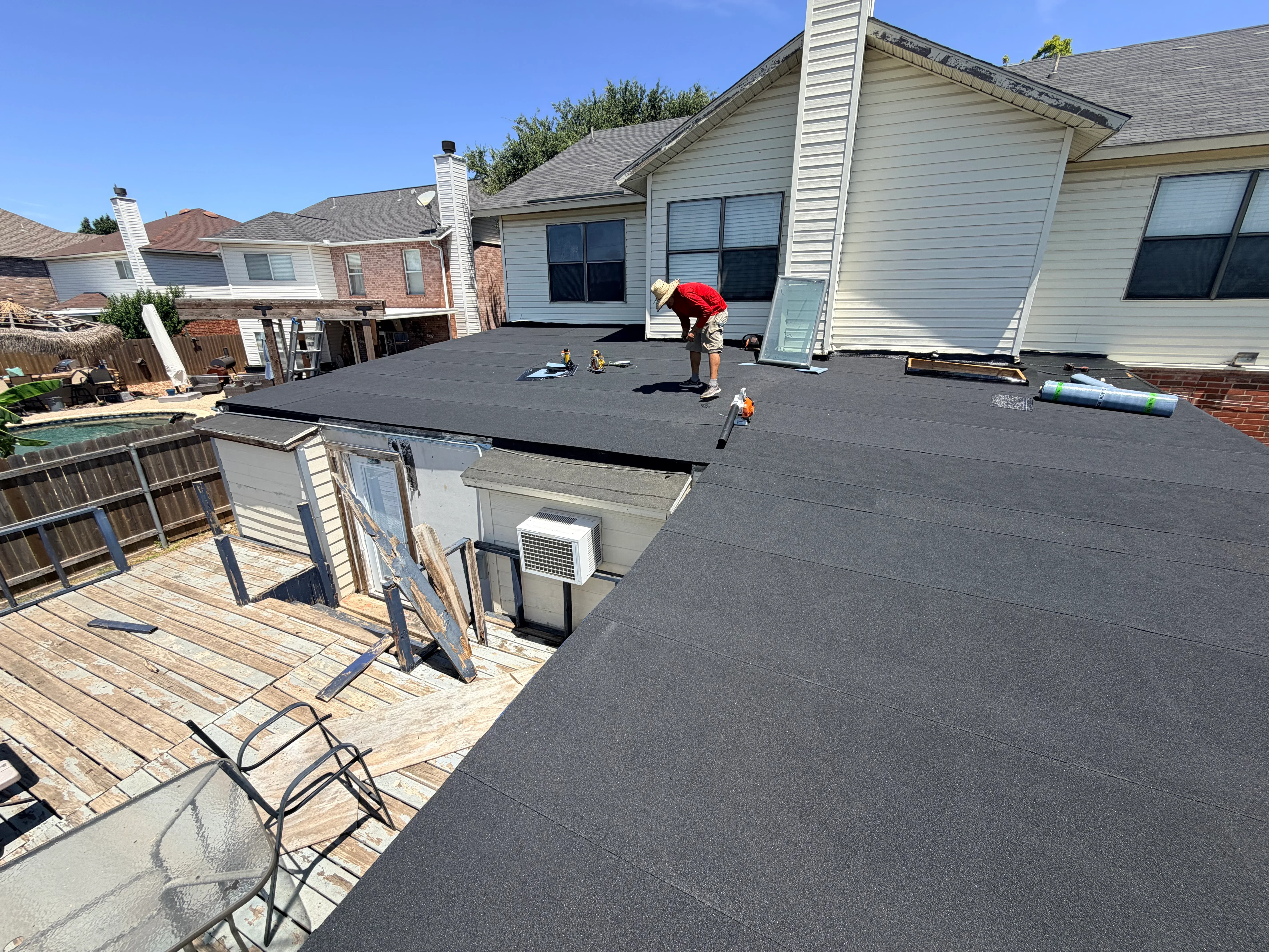 Flat roof installation with dark asphalt membrane material and seamed sections