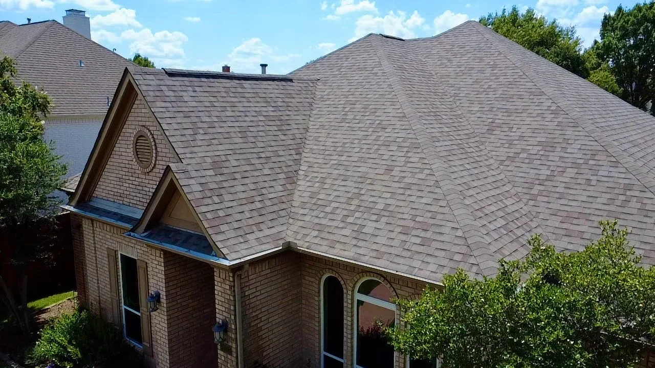 Gray architectural shingle roof with multiple peaks, valleys, and gable vents on brick home