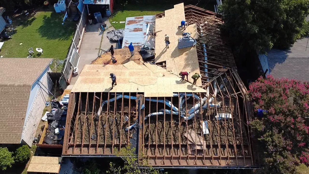 Aerial view of residential roof framing with wood trusses, plywood sheathing, and HVAC installation in progress