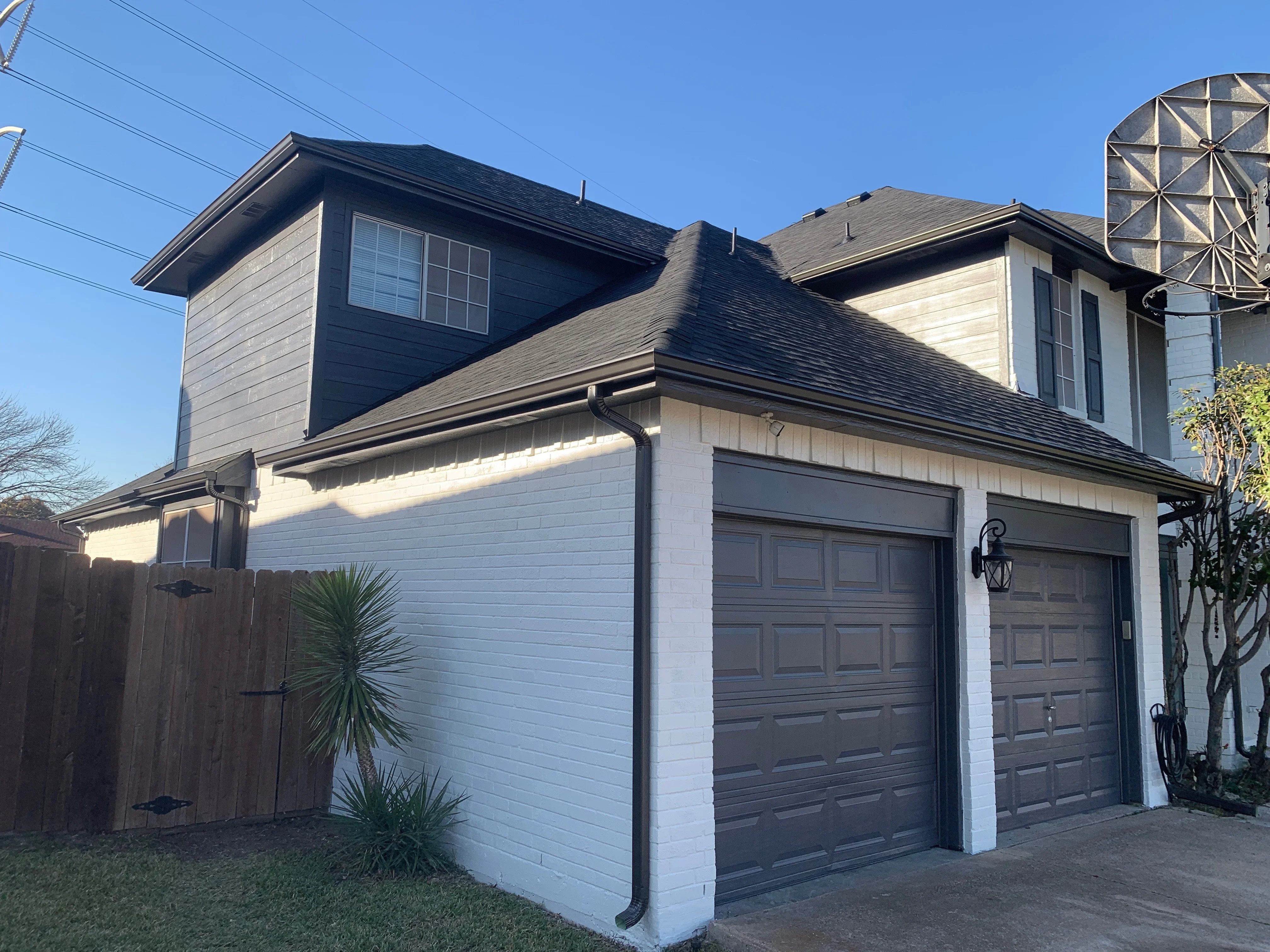 Charcoal gray architectural shingle roof with black gutters and trim on two-story home