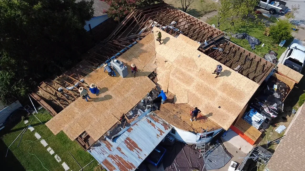 Aerial view of residential roof framing with OSB sheathing and metal bracing during installation