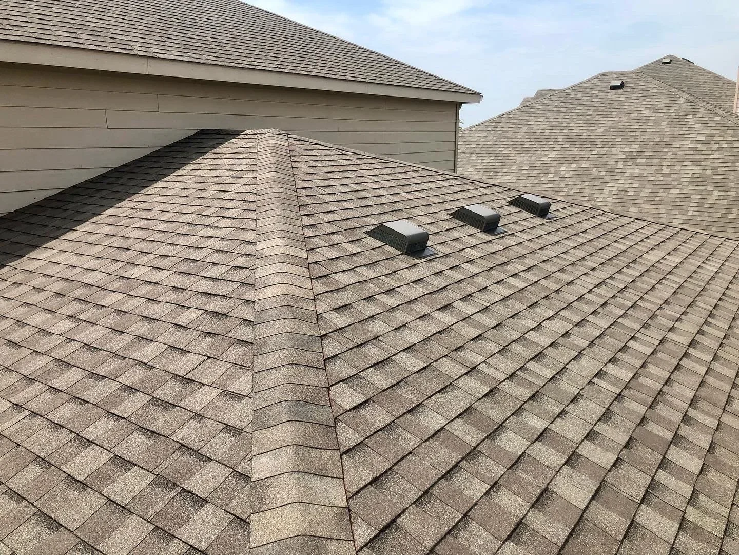 Gray dimensional asphalt shingles installed on multi-plane roof with ridge vents and clean valleys