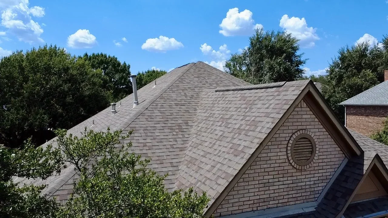 Charcoal gray architectural shingles on multi-pitched roof with brick chimney and proper flashing
