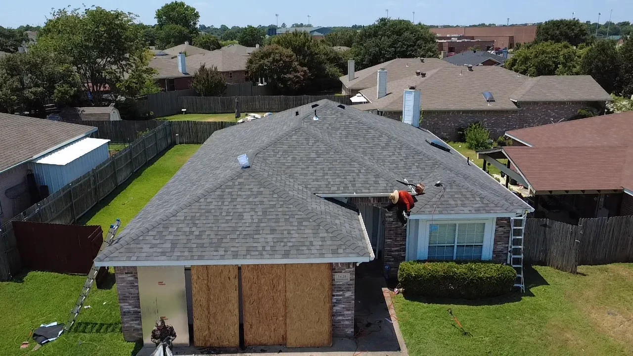 Gray architectural shingles installed on pitched roof with brick home and ridge vents visible
