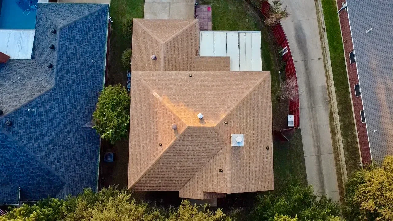 Aerial view of completed architectural shingle roof with multiple peaks and installed ventilation vents