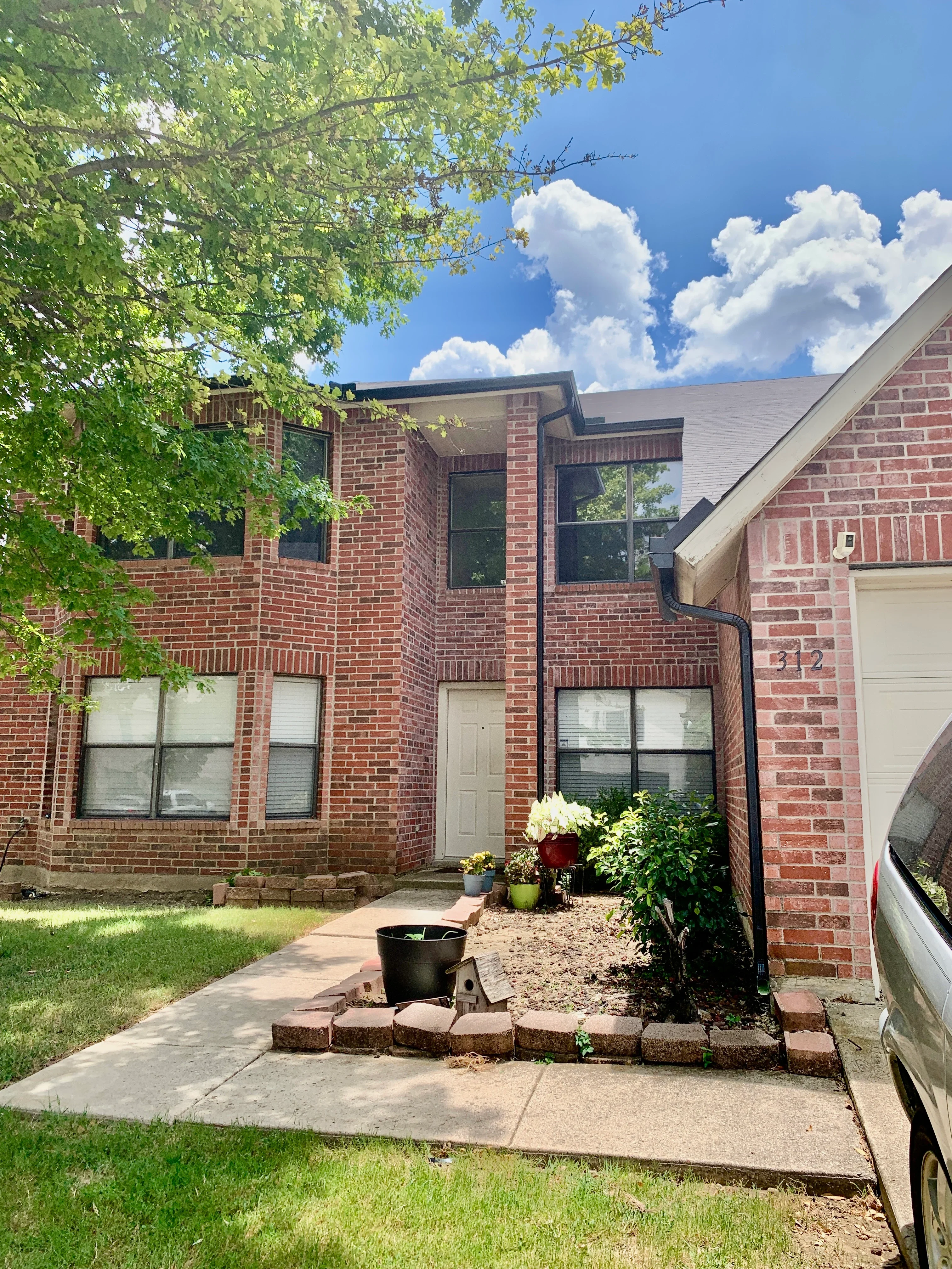 Two-story brick home with new asphalt shingle roof and black gutter system installed