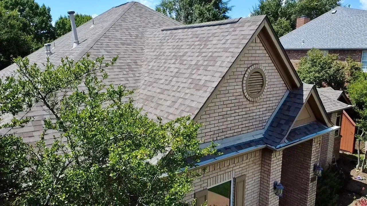Charcoal gray architectural shingles on multi-pitched roof with dormers and brick chimney flashing