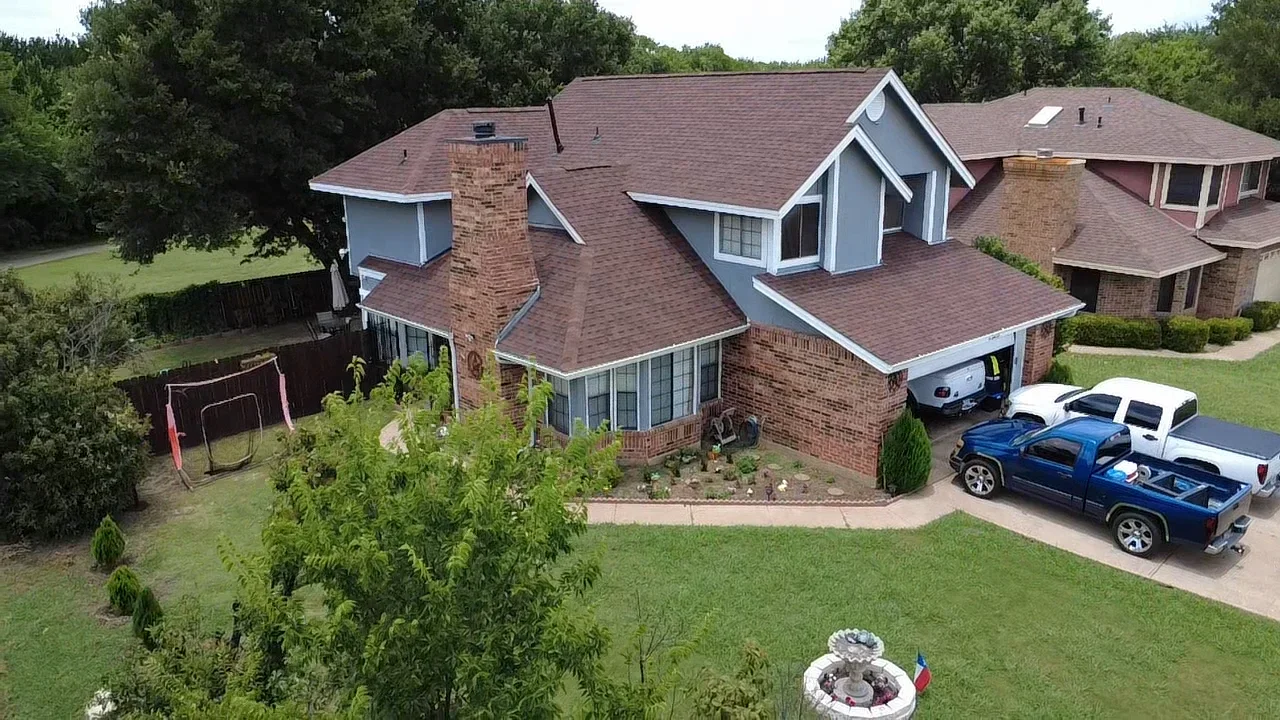 Two-story brick home with new architectural shingle roof installation, multiple roof planes and dormers